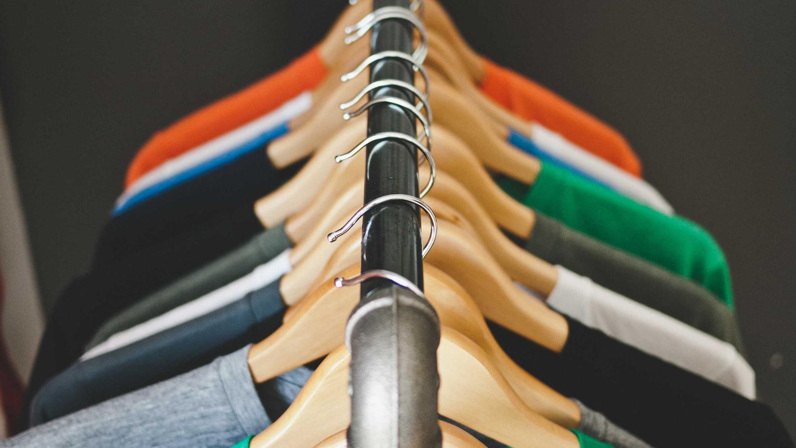 Placeholder image: a row of shirts on wooden hangers on a clothes rail